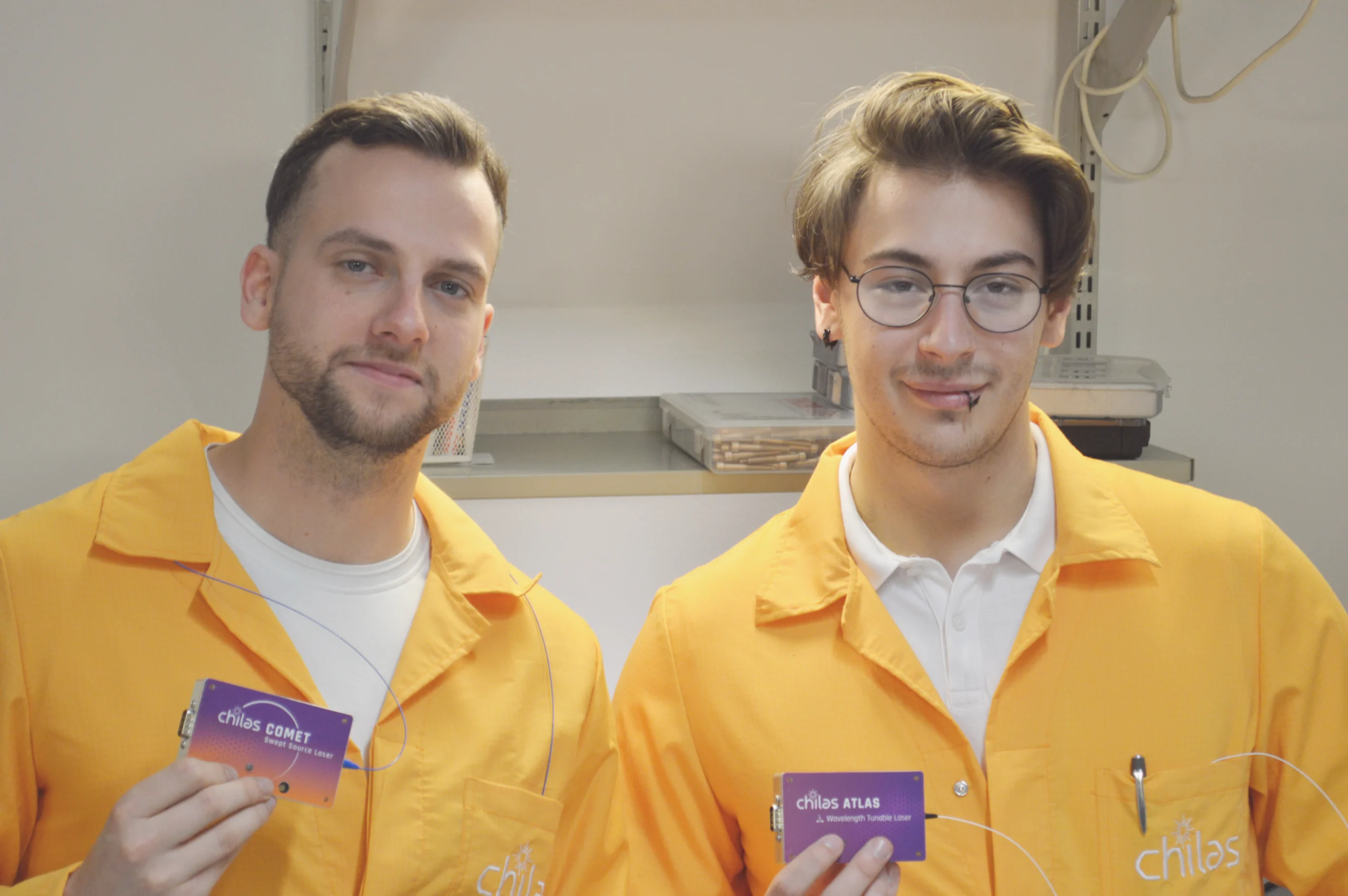 Chilas engineers in orange lab coats holding Chilas tunable lasers