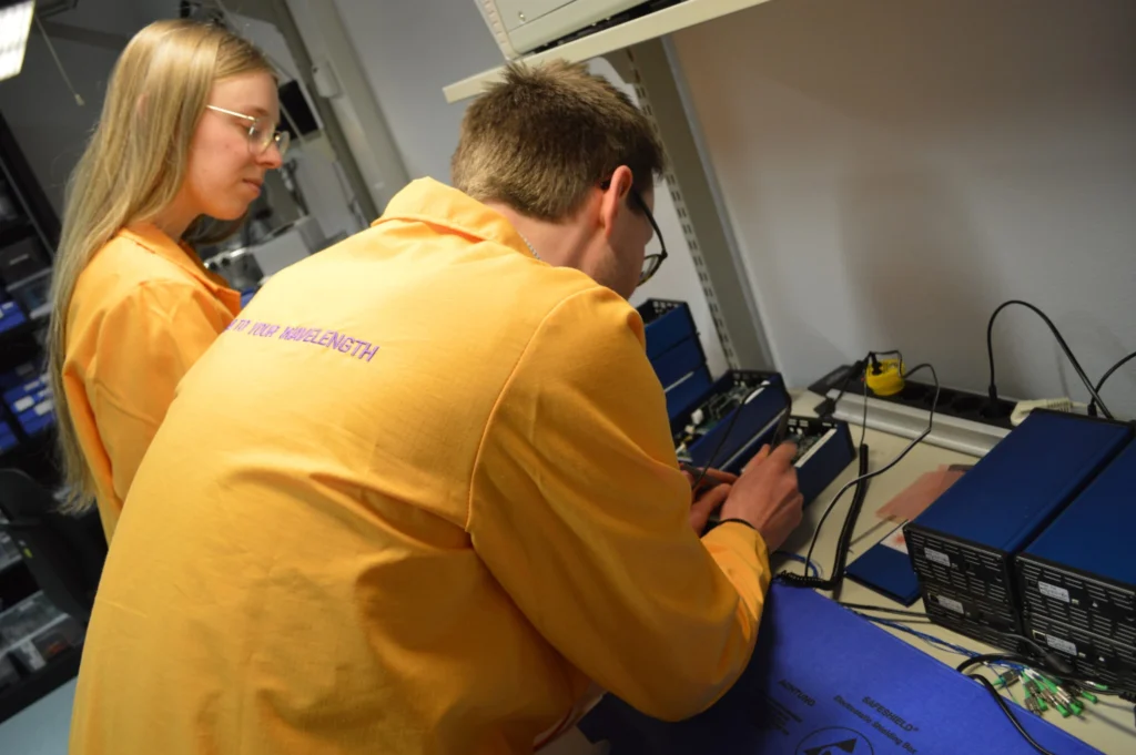 Chilas engineers wearing orange lab coats in the lab, calibrating lasers